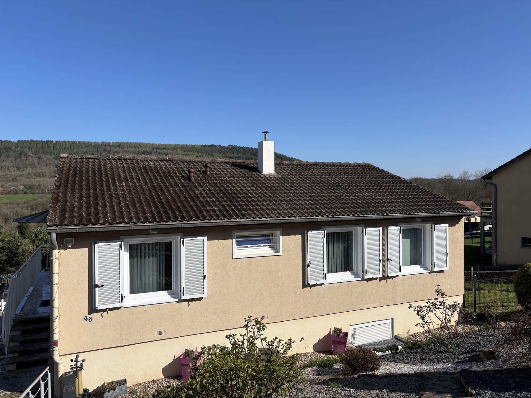 La même maison après les travaux, cheminée blanche, sous un ciel bleu