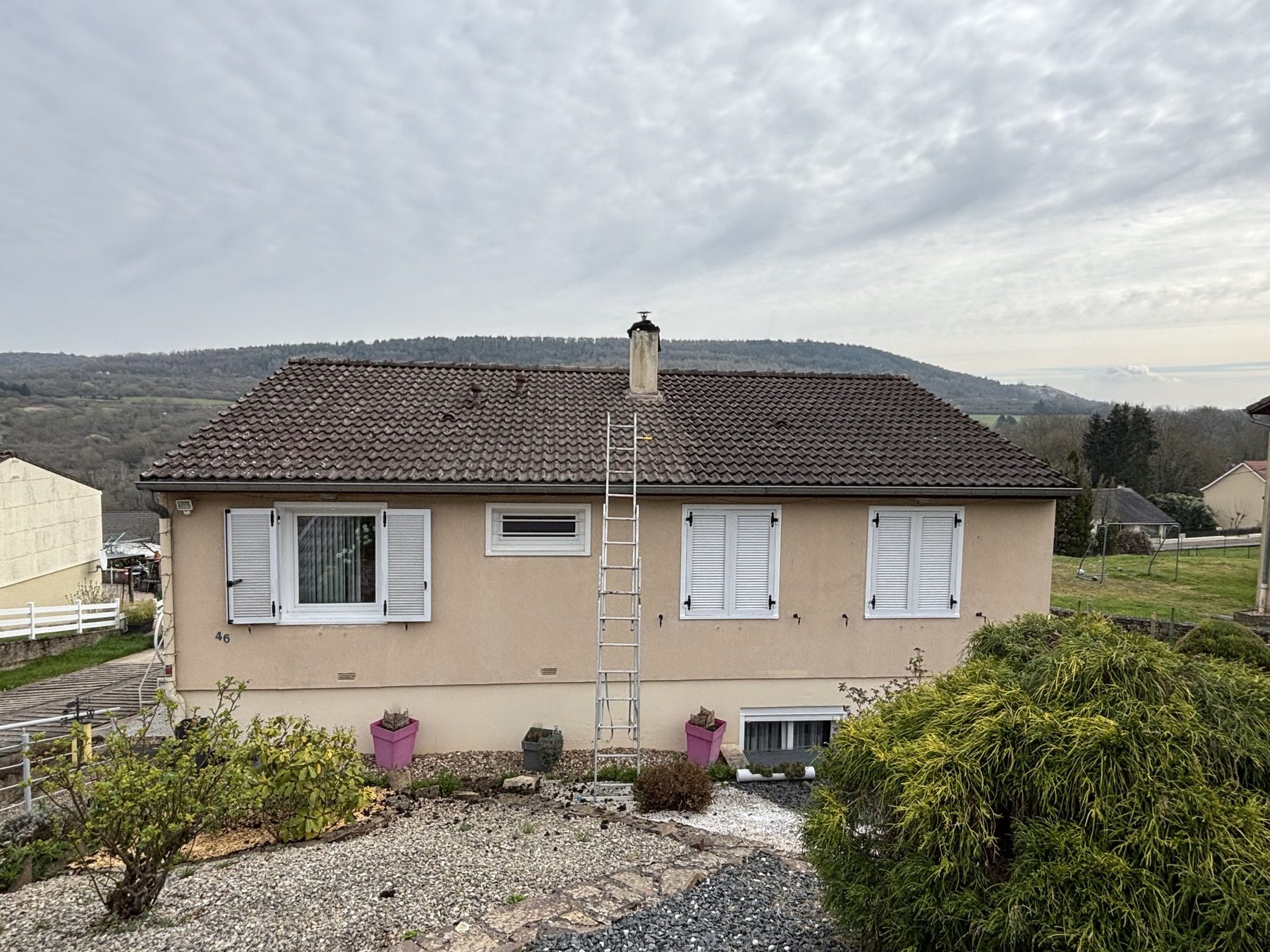 Maison avant les travaux, échelle posée contre la façade, cheminée tachée
