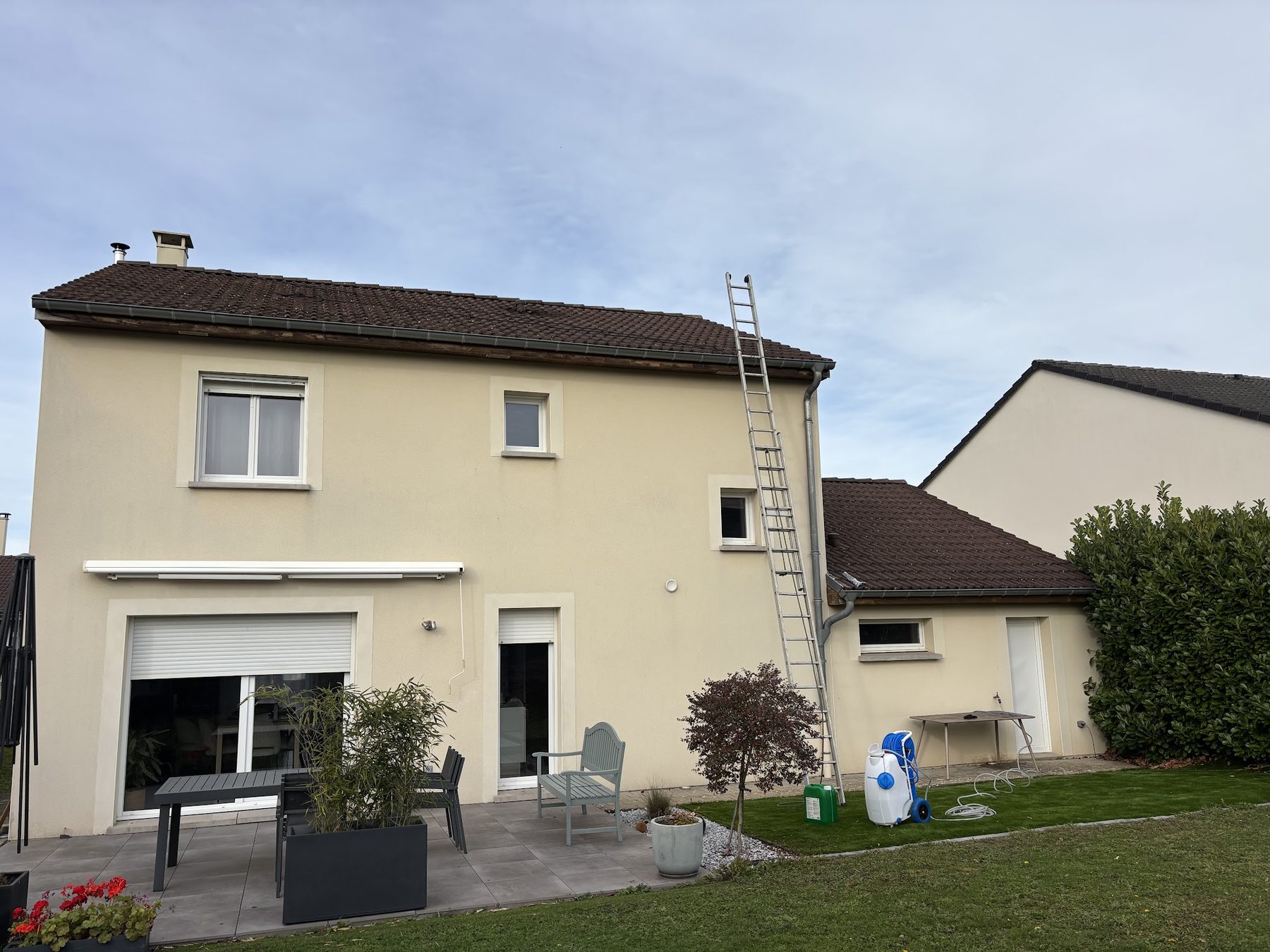 Échelle contre une maison et pulvérisateur de traitement au pied du mur